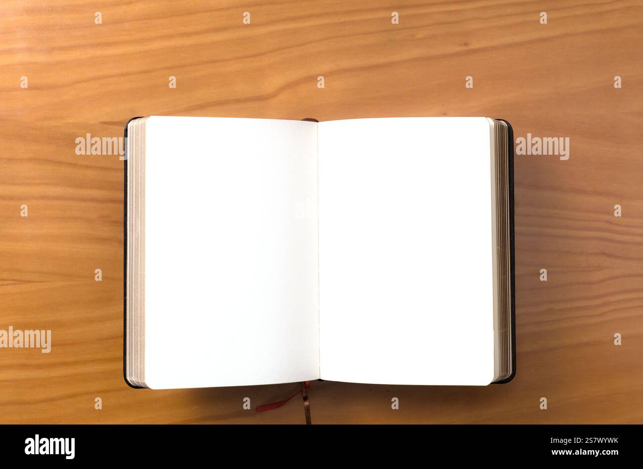 A notebook lies open on a wooden surface, featuring blank pages ready for writing or sketching. Stock Photo