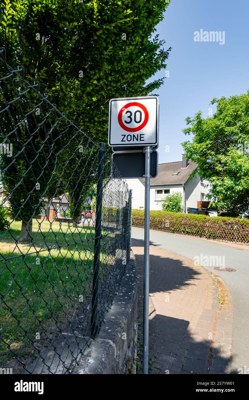 A sign with a red circle and white number 30 on it is posted on a pole ...