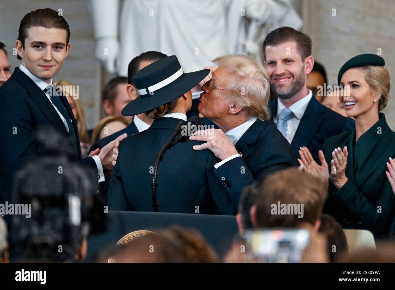President Donald Trump, center right, reaches to kiss wife Melania
