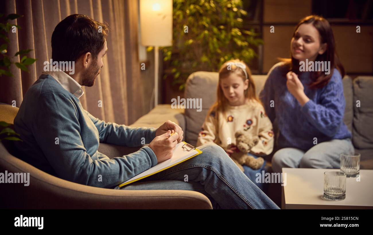Child, girl sits next to her mother during therapy session, holding toy ...