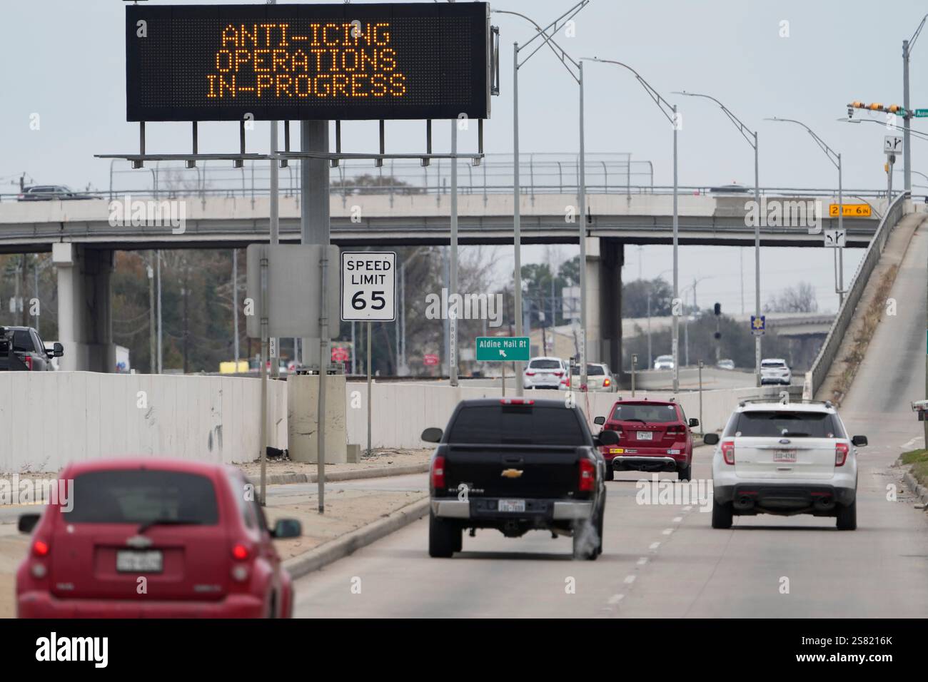 Vehicles pass a sign displaying Winter storm related operations Monday