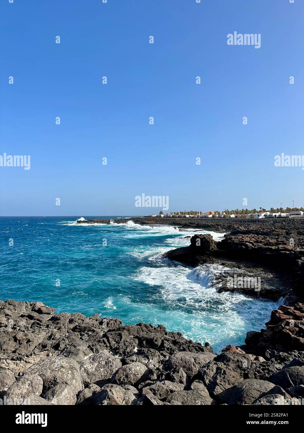 Scenic view of sea waves against rocky cliff featuring a clear blue sky - Smartphone Captured Stock Image