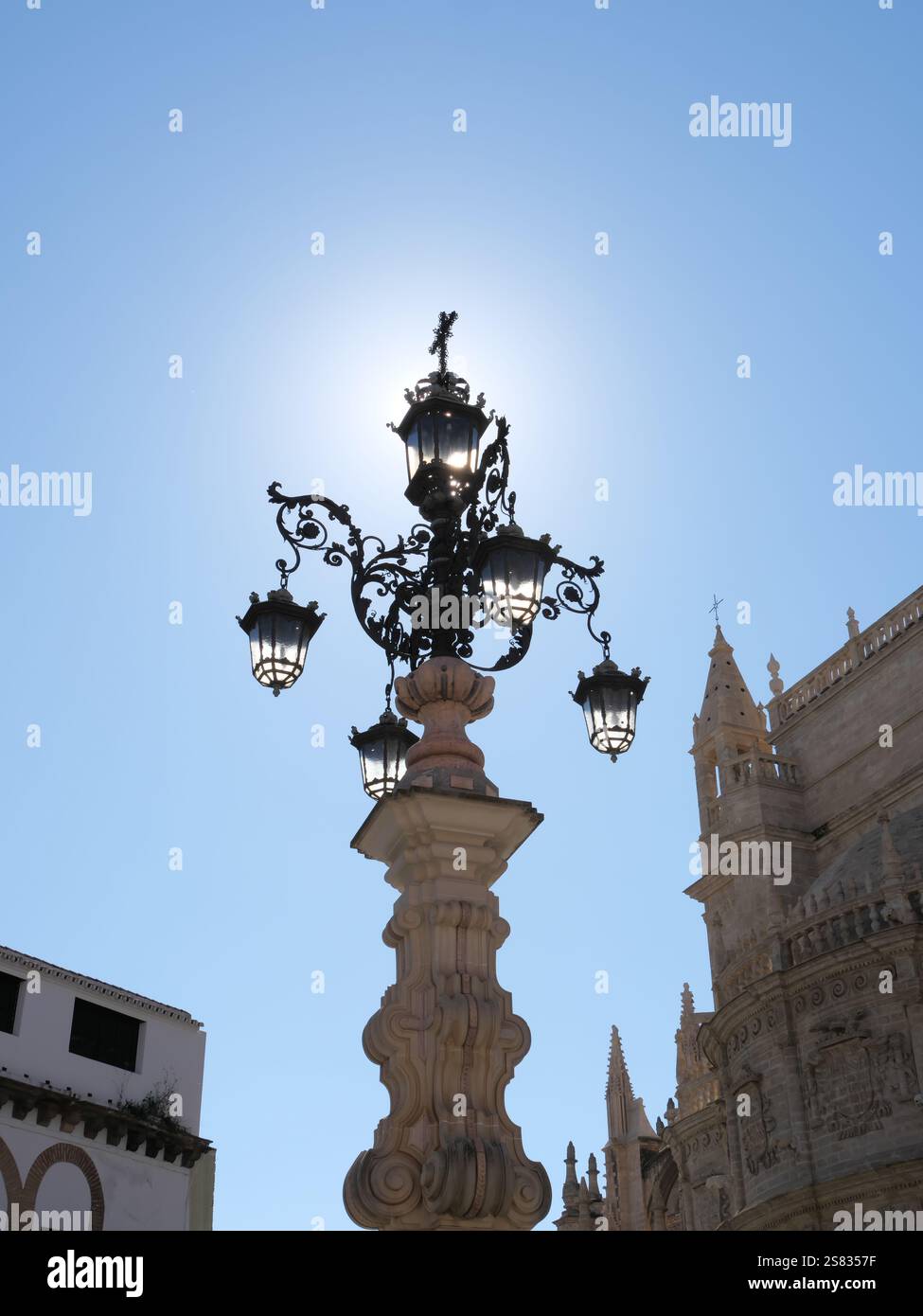 Lamppost of the Fuente de la Farola with many lamps in the backlight on the Plaza de la Virgen de los Reyes in Seville Spain Stock Photo