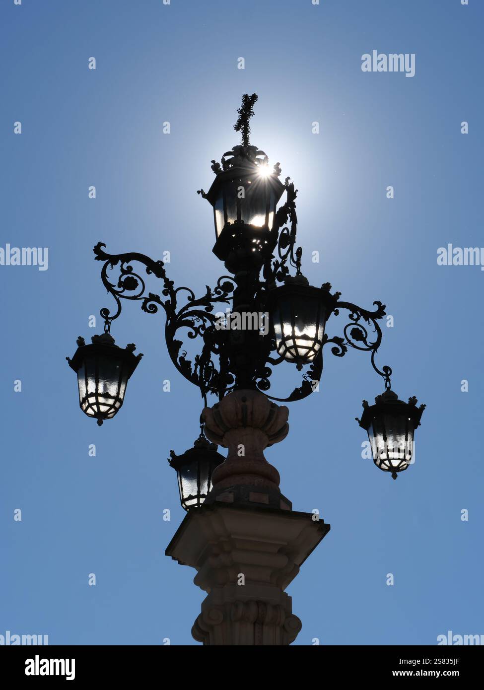 Lamppost of the Fuente de la Farola with many lamps in the backlight on the Plaza de la Virgen de los Reyes in Seville Spain Stock Photo