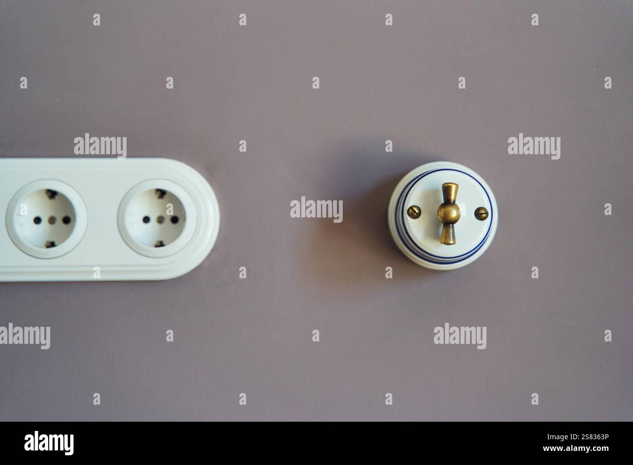 Retro style light switch and socket on dark pink wall Stock Photo