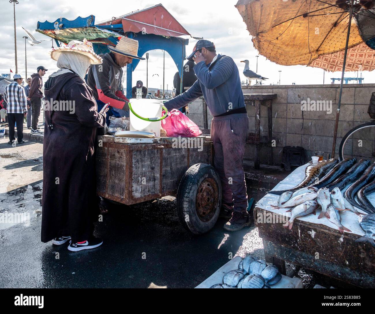 Local shoppers negotiate prices for fresh fish at the lively market in Essaouira, Morocco, Stock Photo