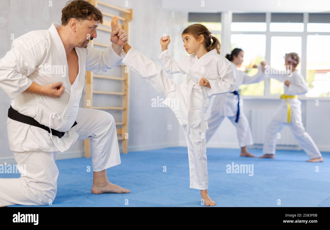 Preteen Girl In Kimono Practicing Karate Kicks During Sparring With preteen-girl-in-kimono-practicing-karate-kicks-during-sparring-with