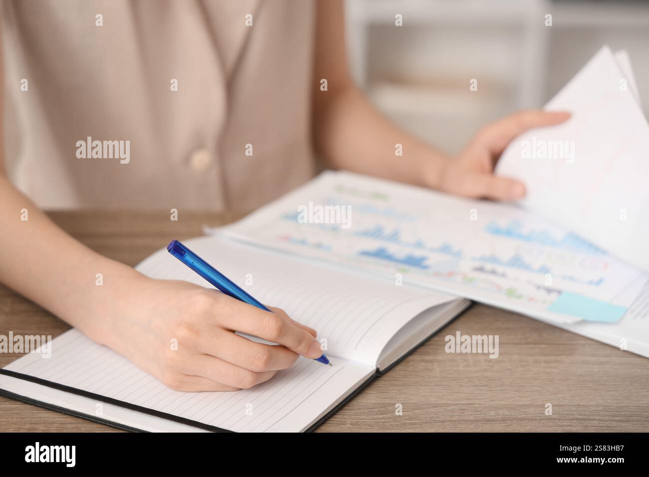 Young woman writing down something while working with documents in office. Closeup Stock Photo
