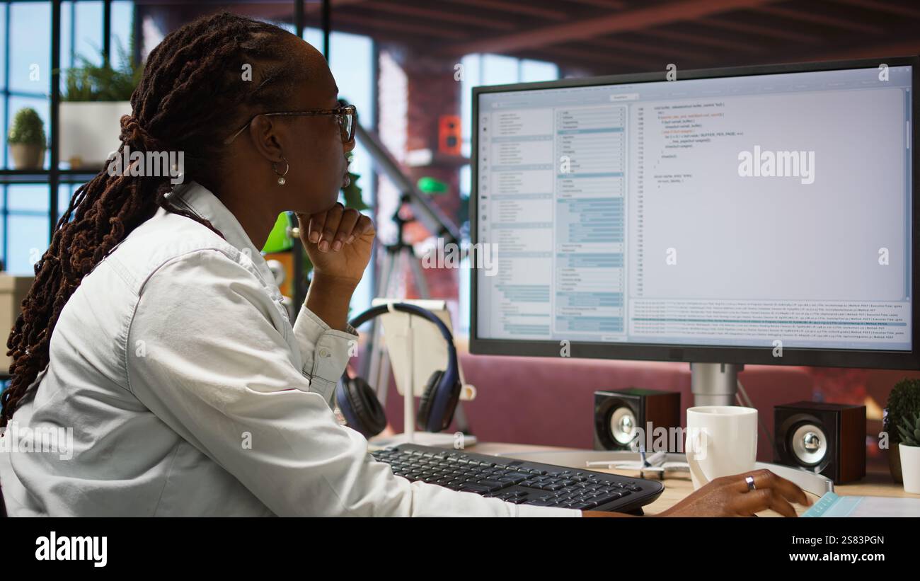 Woman feeling worried while looking at UI on PC screen, having trouble executing programming code. Anxious IT developer concerned by errors popping up while testing code in apartment, camera A Stock Photo