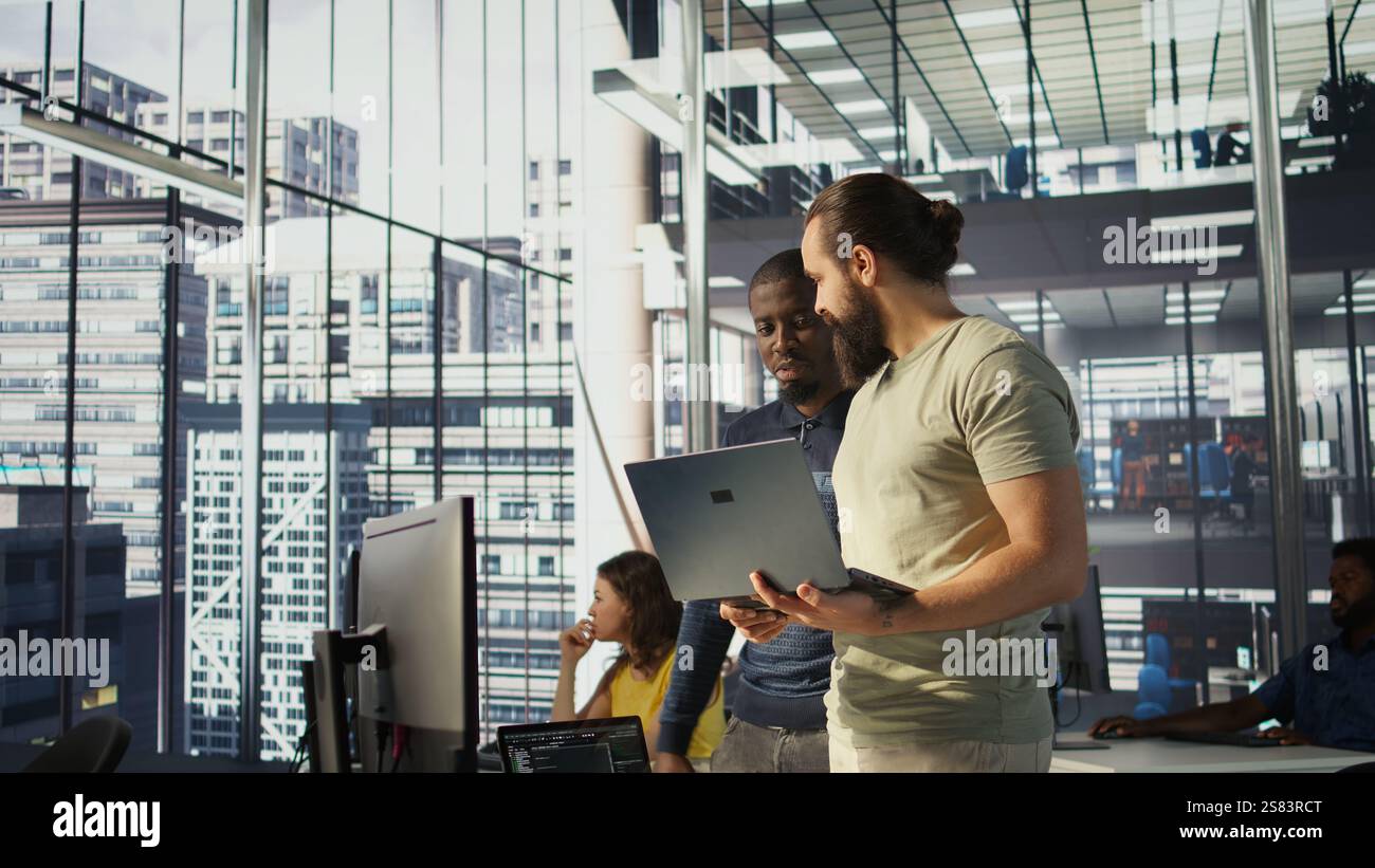 Programmer and colleague conducting experiments and tests to optimize machine learning models for performance and accuracy. IT staff members in office analyzing and interpreting complex data, camera B Stock Photo