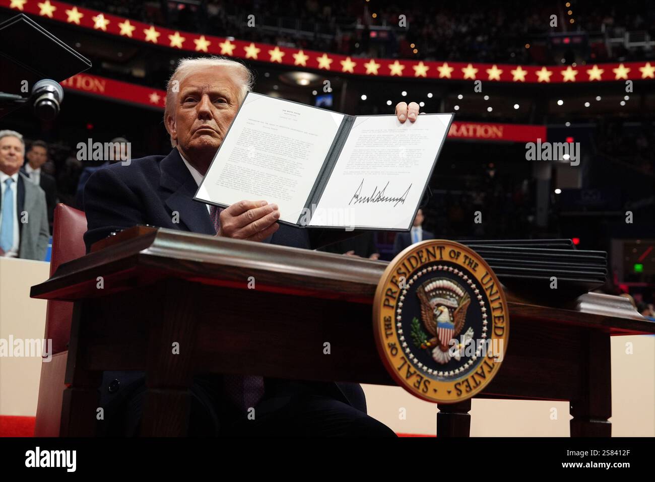 President Donald Trump signs an executive order on a hiring freeze as