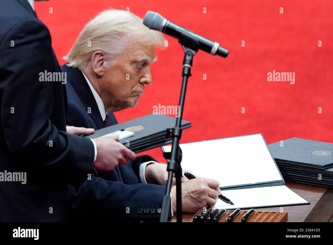 President Donald Trump signs an executive order at an indoor