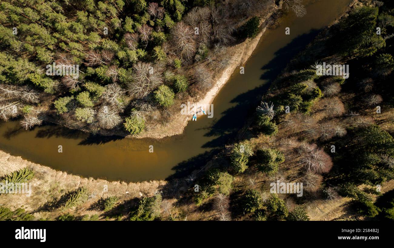 Aerial perspective of a river curving through a forest with evergreen ...