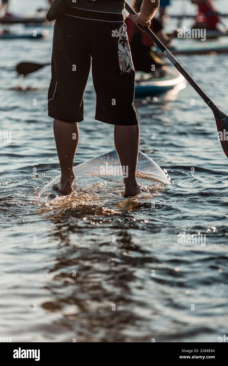 Shallow Paddle A person on a paddleboard holds a paddle in shallow water, wearing ...