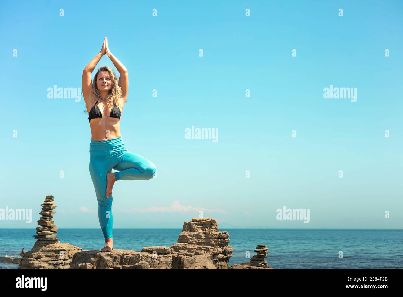 Yoga woman standing in vrikshasana tree pose hand namaste on cliff at ...