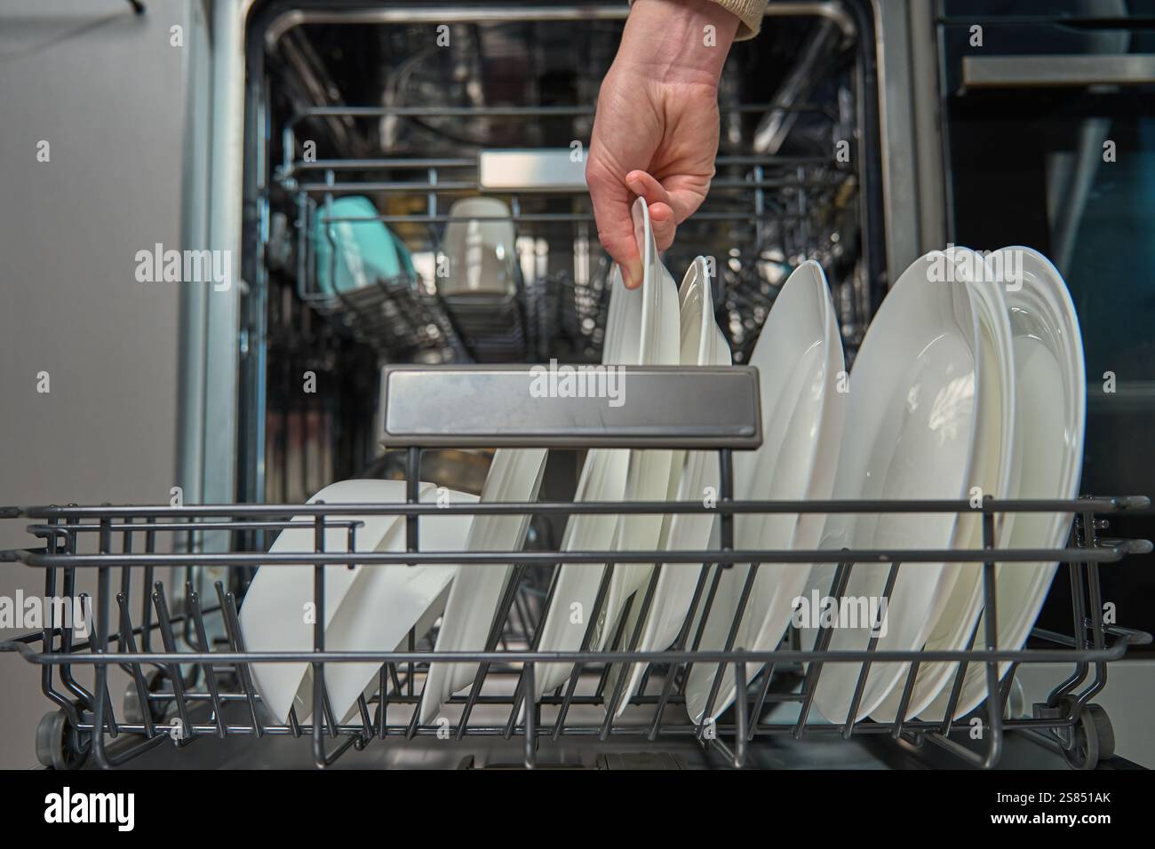 woman-unloading-clean-white-plates-from-the-bottom-rack-of-dishwasher