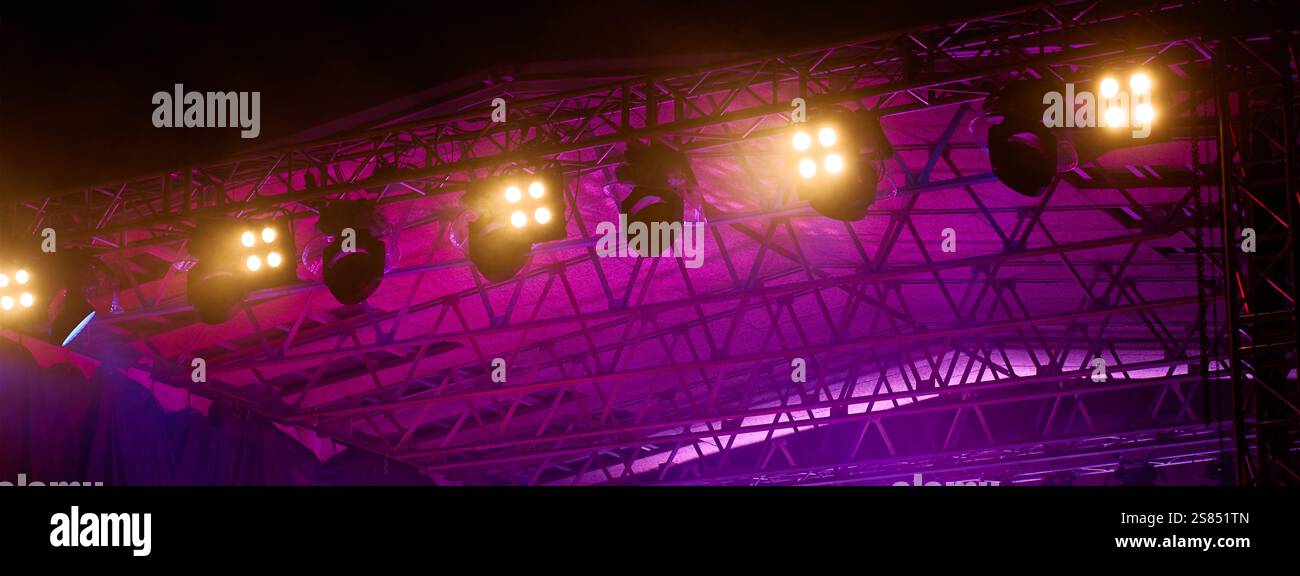 Close-up view of professional stage lighting mounted on metal truss. Bright spotlights at concert stage. Live music event Stock Photo
