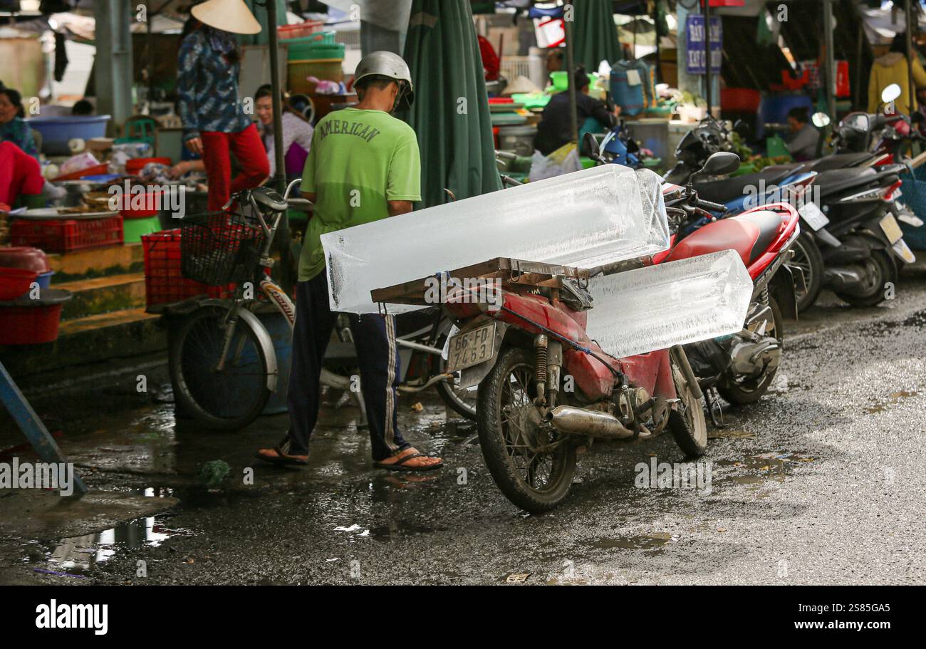 A Vietnamese ice seller delivers large blocks of ice on his motorbike to his customers at the local market in Sa Dec, Mekong Delta region, Vietnam Stock Photo
