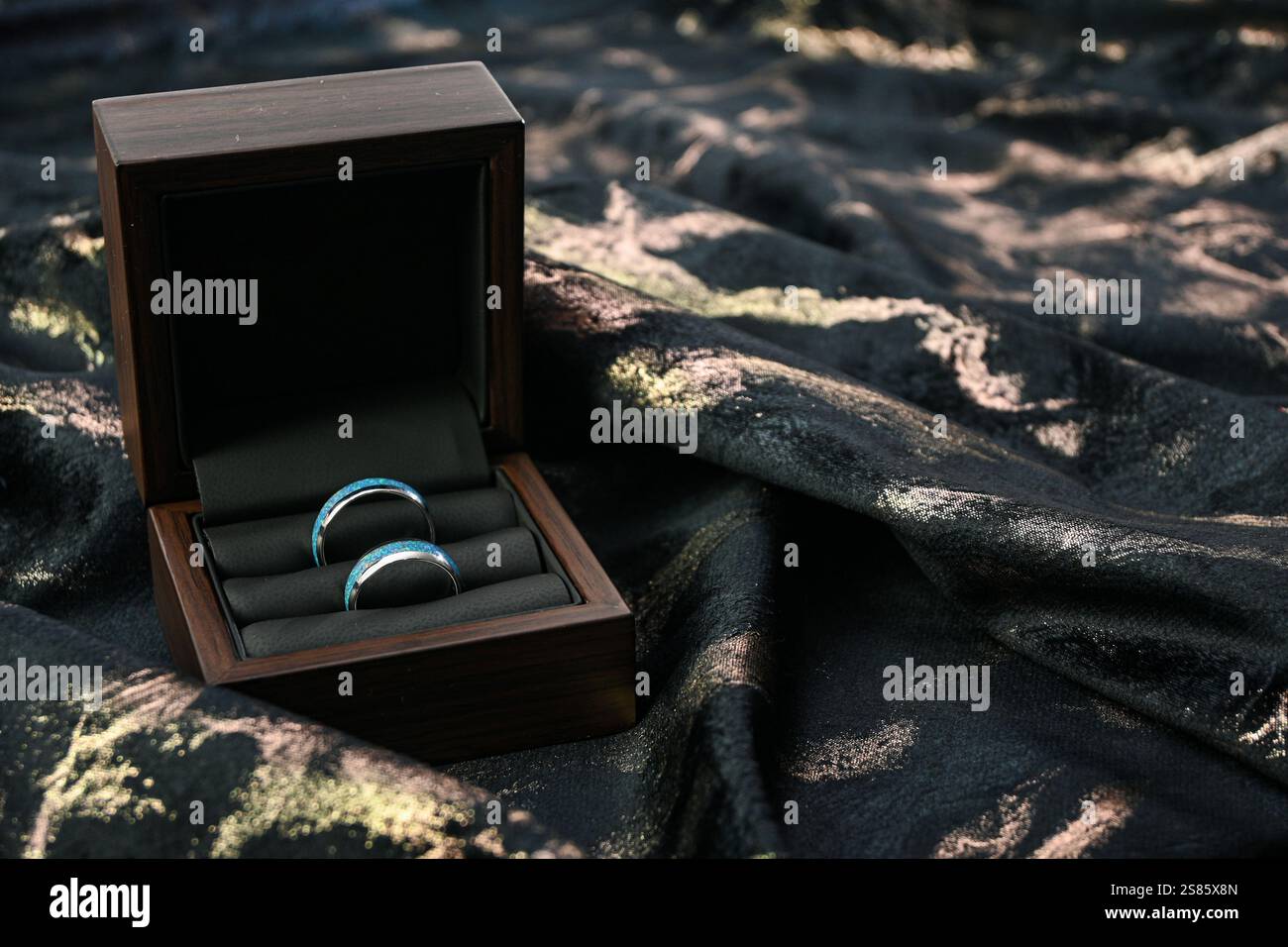 Wedding rings with turquoise inlay are presented in an elegant wooden ...