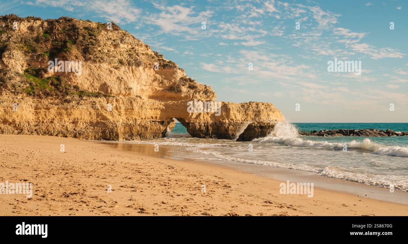 Stunning coastal cliff with a natural arch by the sparkling ocean waves ...
