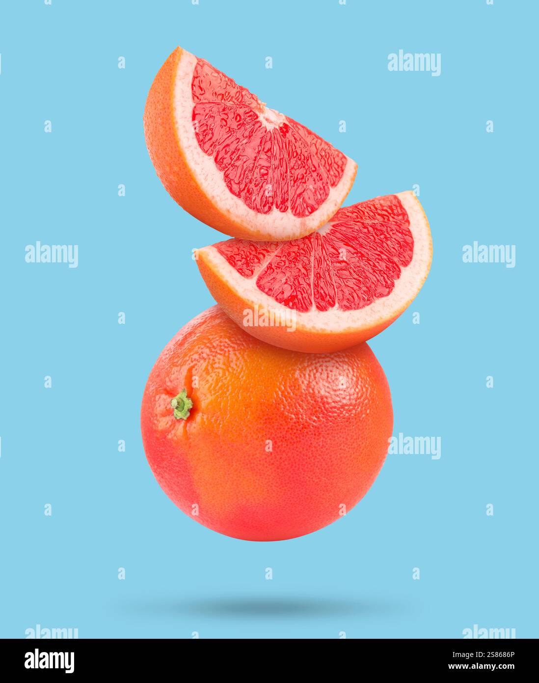 Fresh grapefruits in air on light blue background Stock Photo