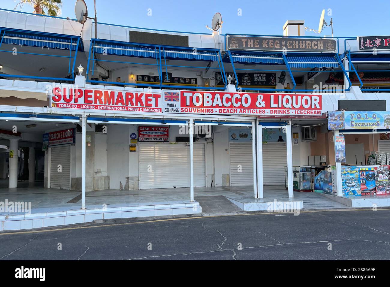 Supermarket near Puerto Colon, with a Tobacco and Liquor Sign.  A British Sports Bar called 'The Keg and Church' can be seen above. 13th January 2025. - Smartphone Captured Stock Image