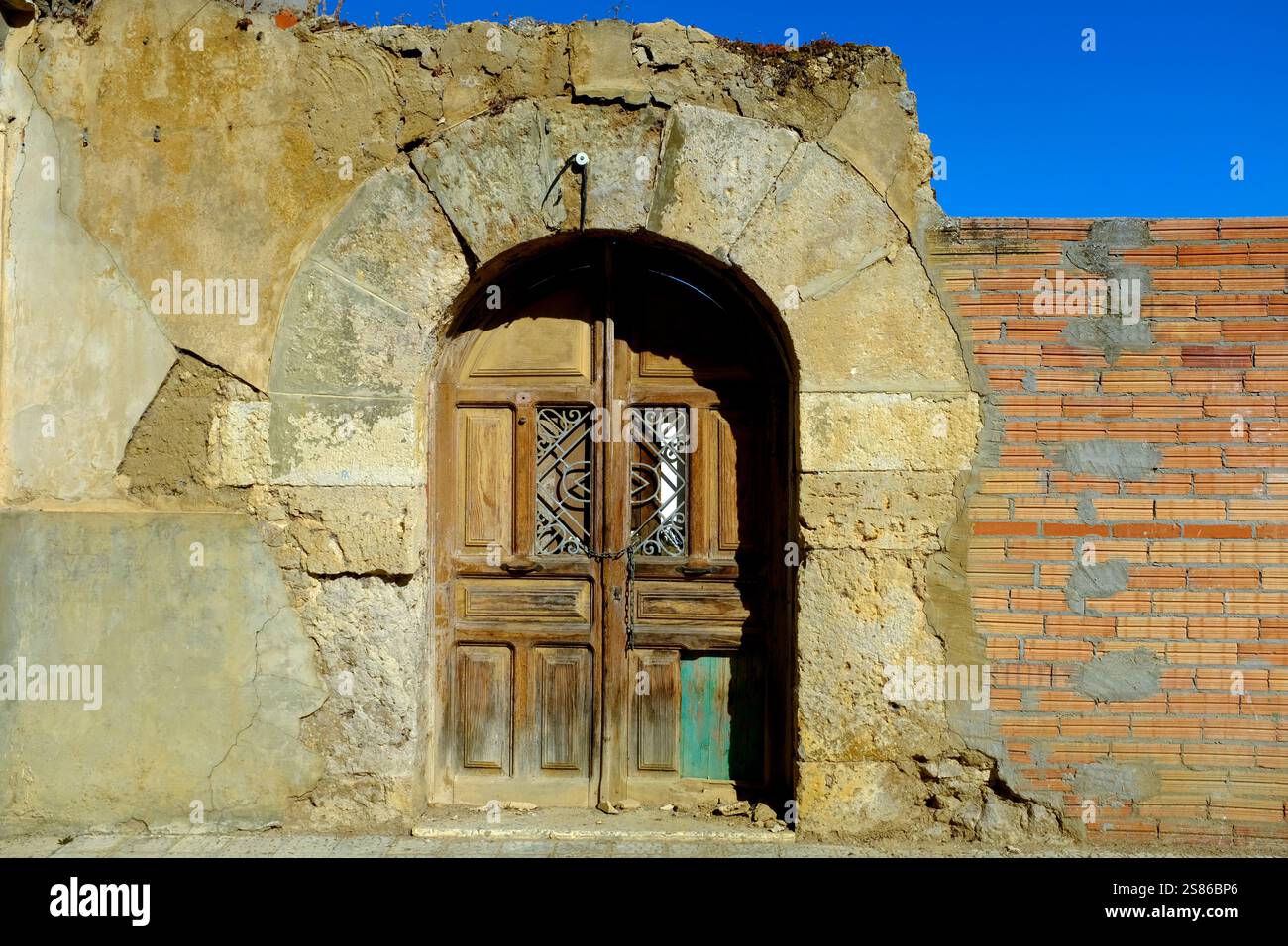 Old wooden door in a stone archway and mixed building material wall, Monzón de Campos, Palencia Province, Castile y Leon, Spain Stock Photo