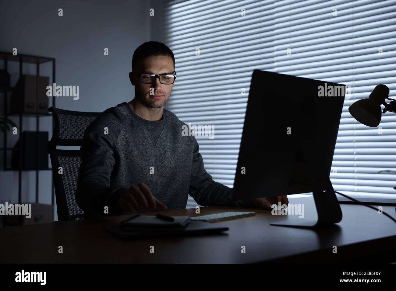 Programmer working on computer indoors at night Stock Photo