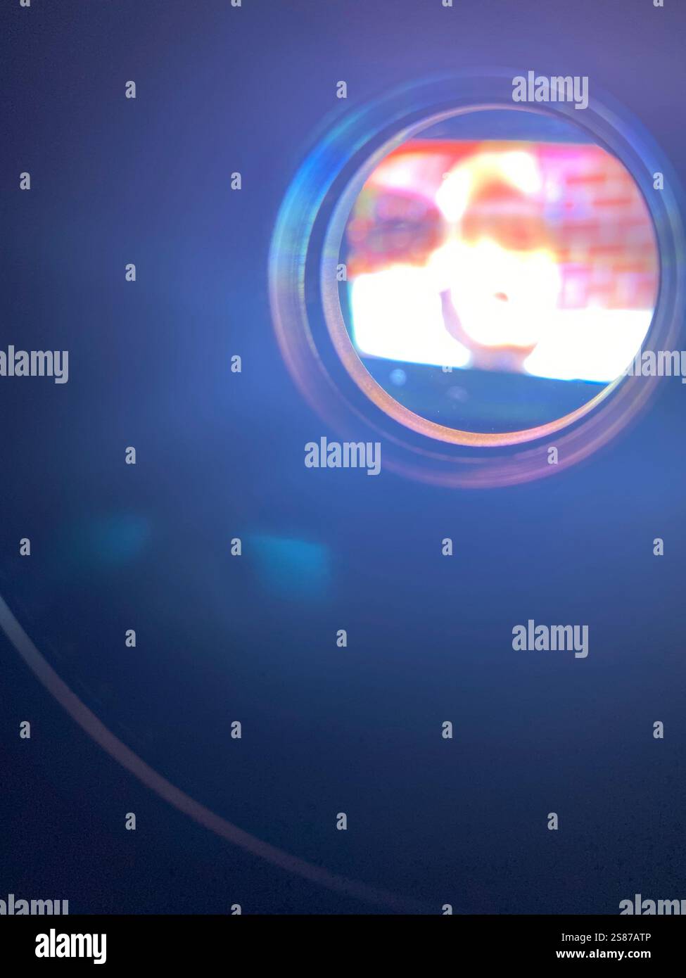 olhando dentro de um miniprojetor, com os olhos de um curiosos, percebi a fonte da imagem invertida na parede! Stock Photo