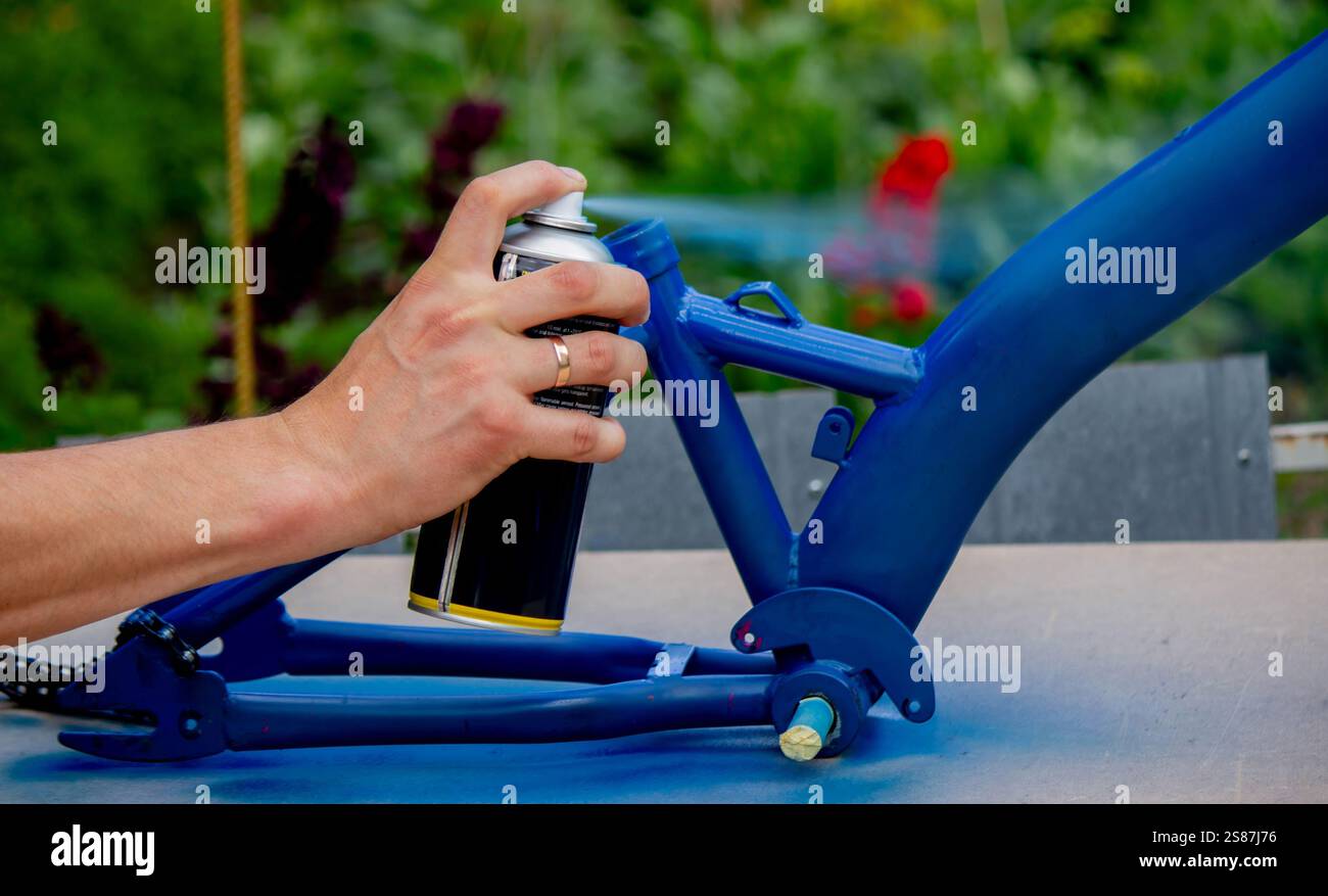 Spray Painting a Bicycle Frame Outdoors. Stock Photo