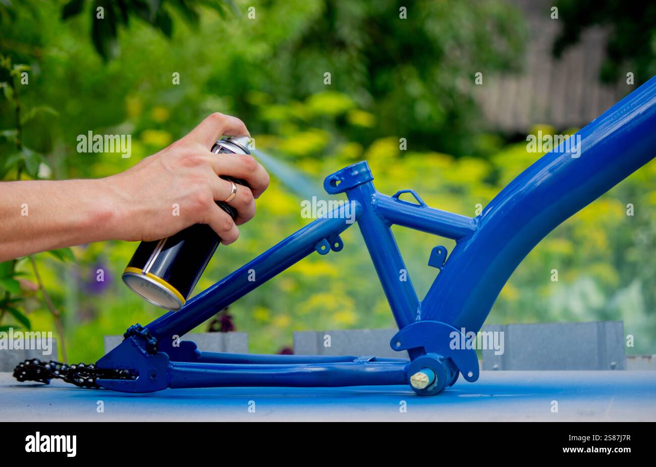 Spray Painting a Bicycle Frame Outdoors. Stock Photo