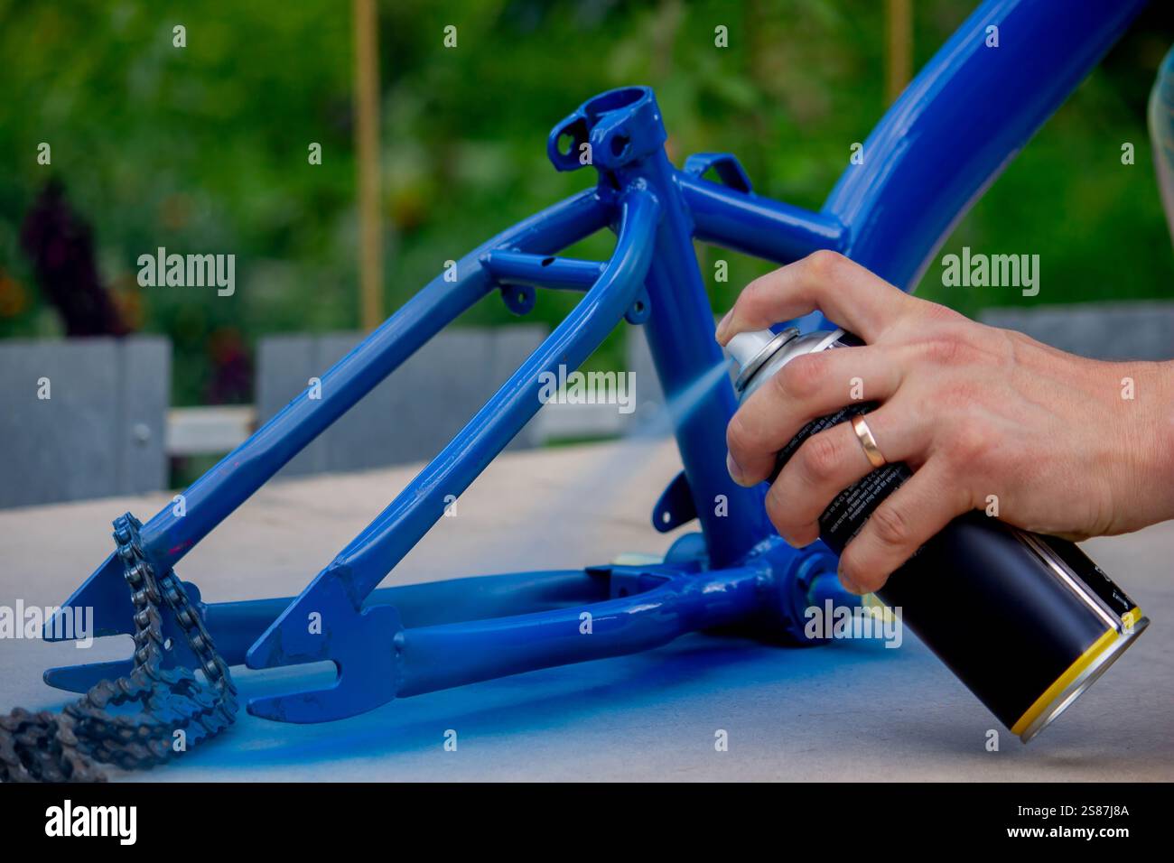 Spray Painting a Bicycle Frame Outdoors. Stock Photo