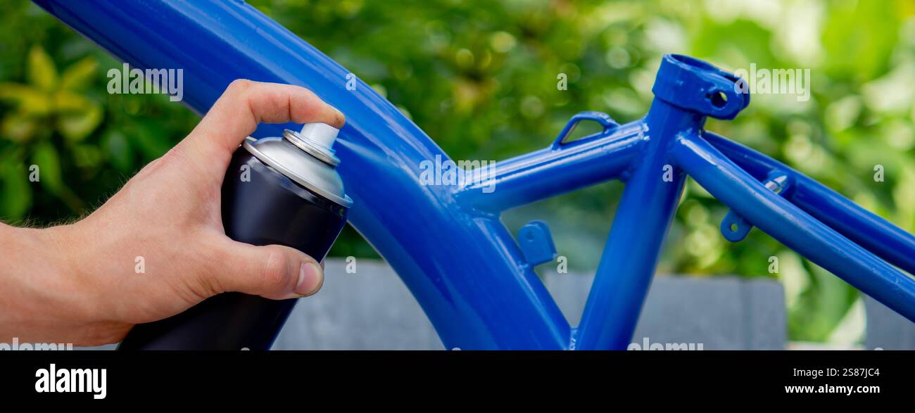 Spray Painting a Bicycle Frame Outdoors. Stock Photo
