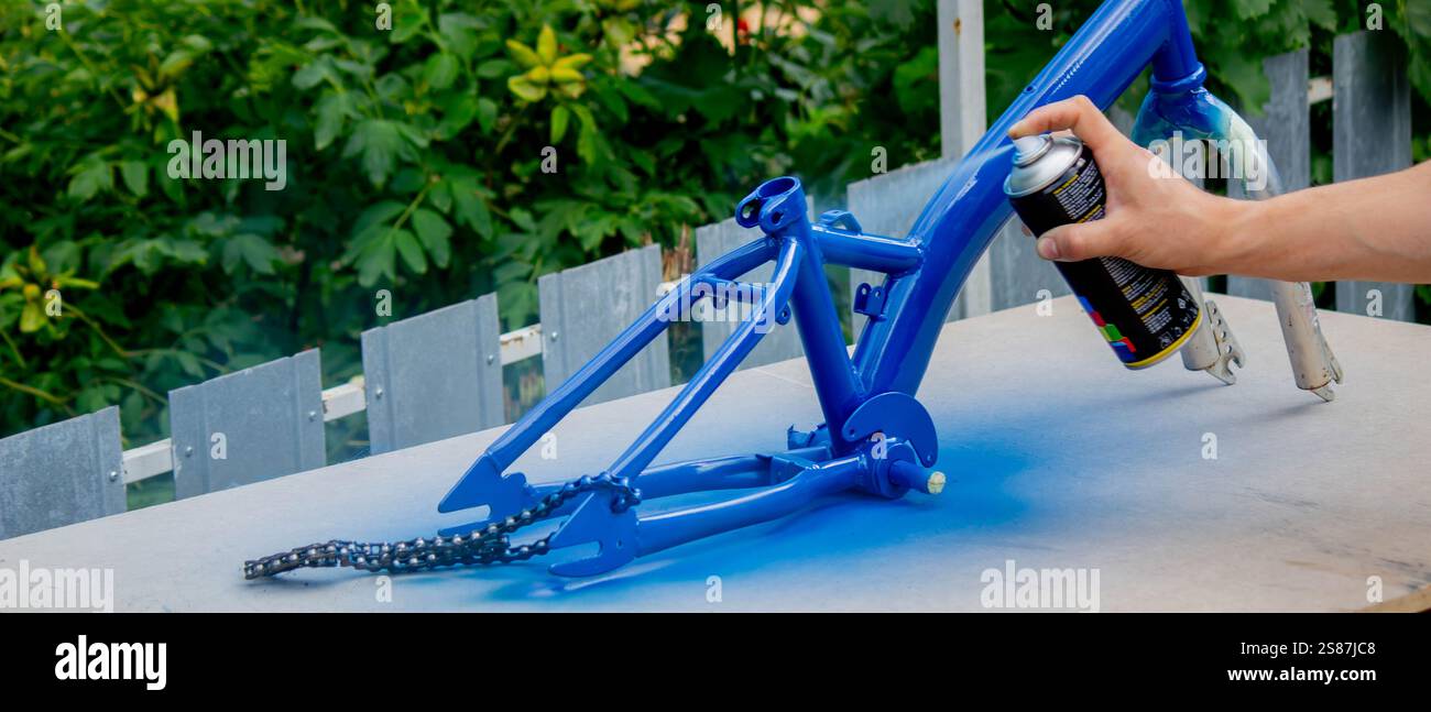 Spray Painting a Bicycle Frame Outdoors. Stock Photo
