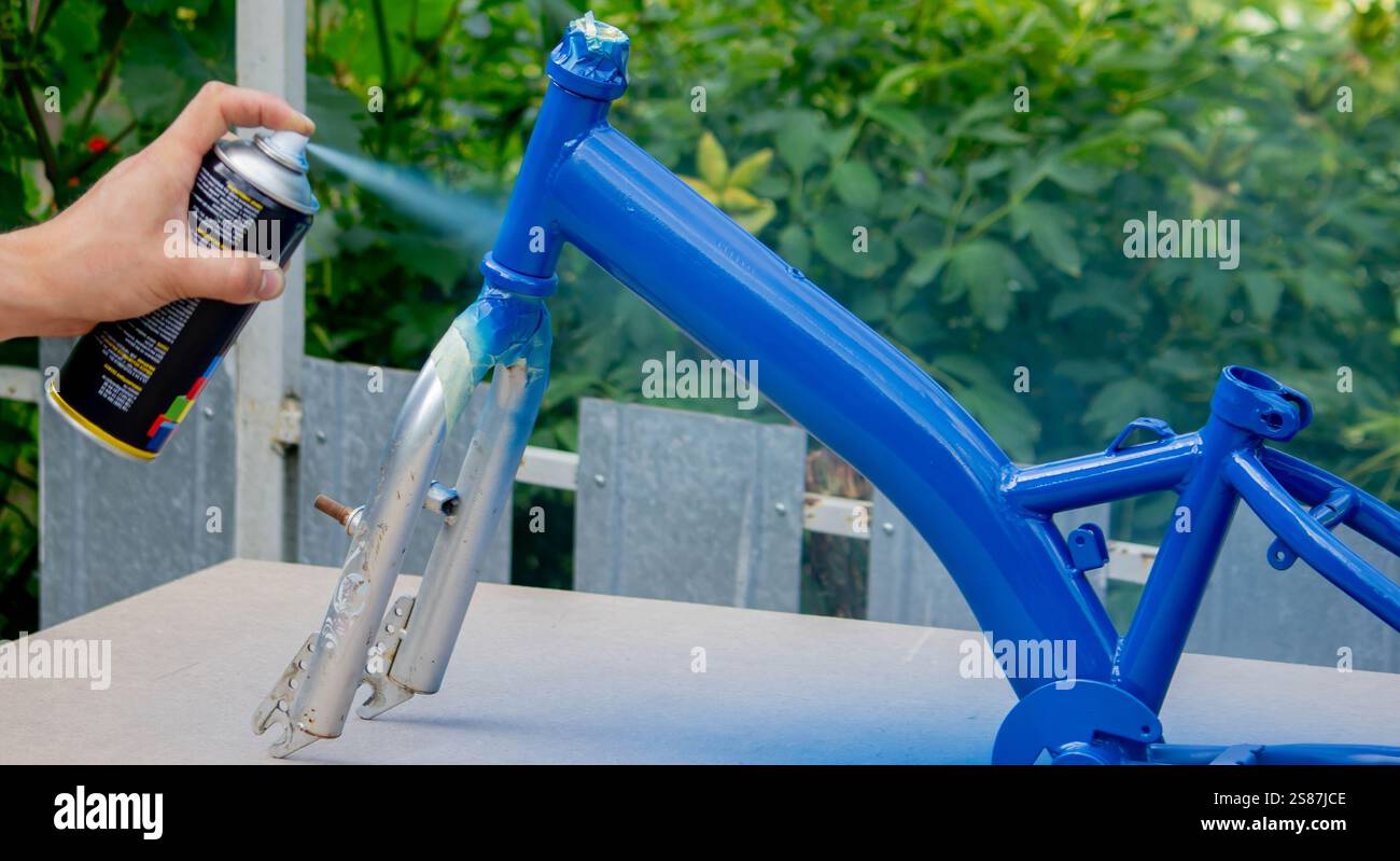 Spray Painting a Bicycle Frame Outdoors. Stock Photo