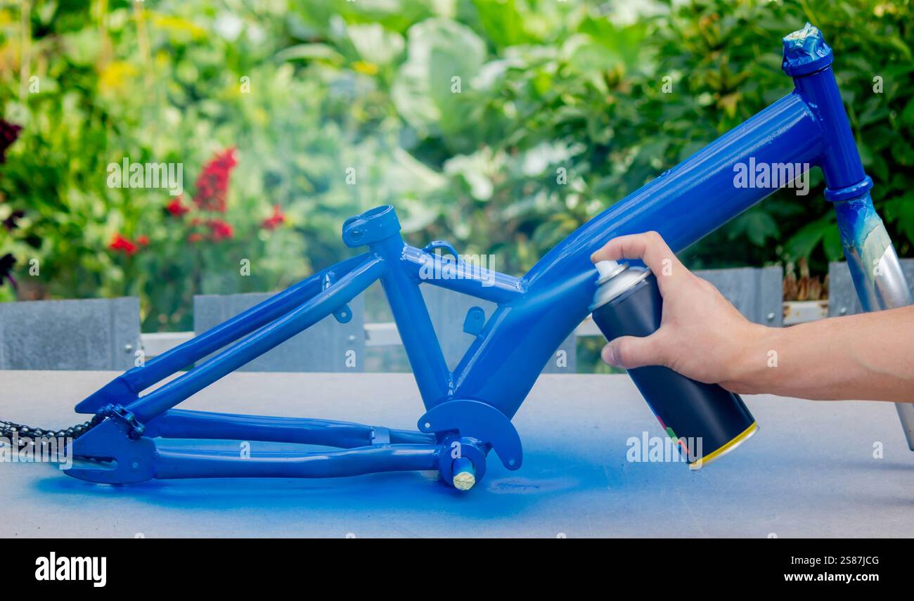 Spray Painting a Bicycle Frame Outdoors. Stock Photo