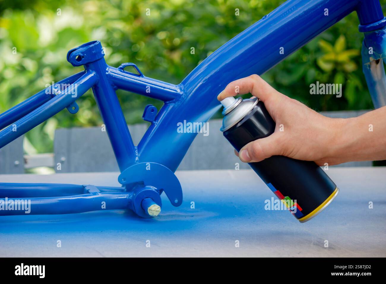 Spray Painting a Bicycle Frame Outdoors. Stock Photo