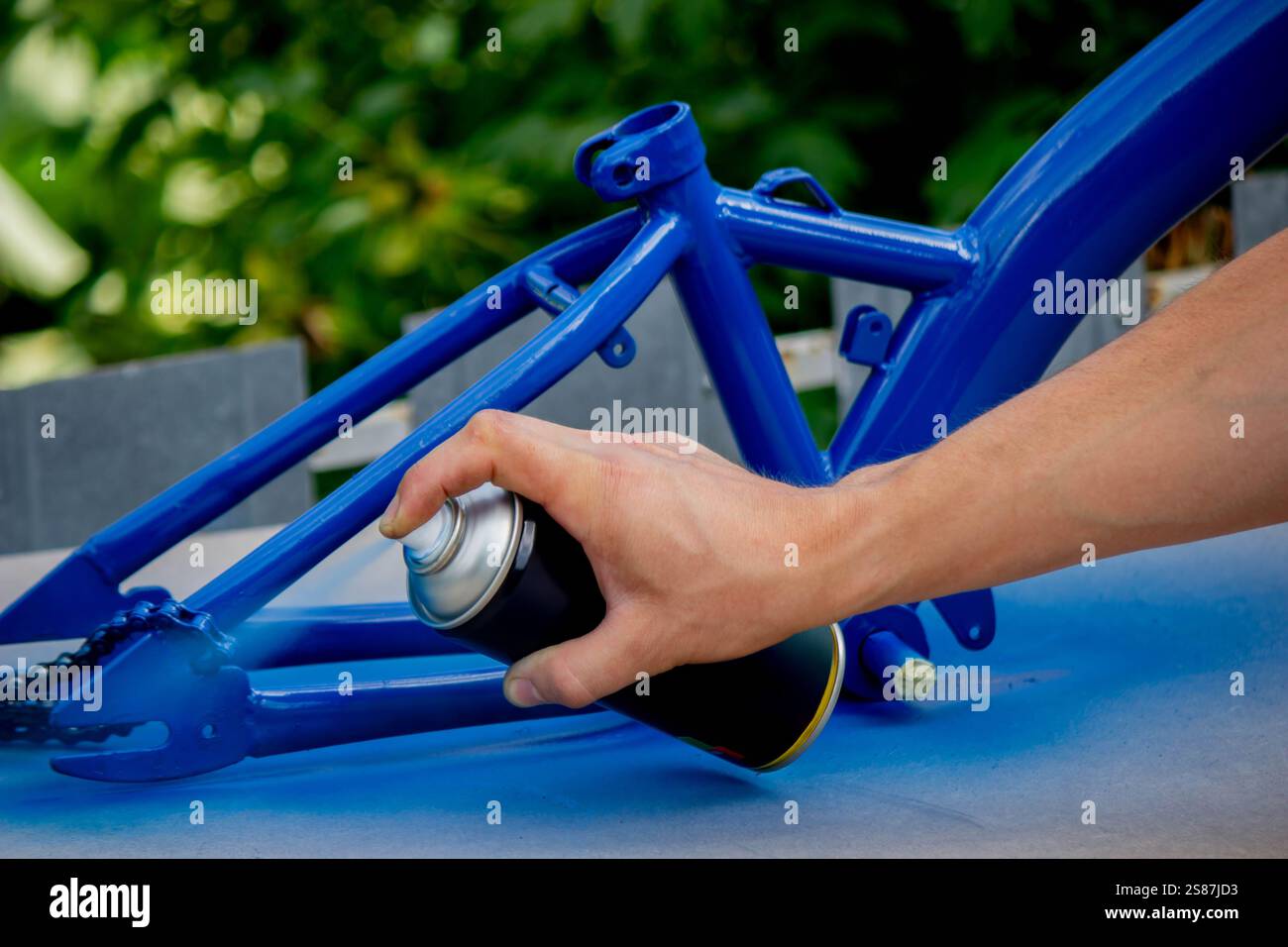 Spray Painting a Bicycle Frame Outdoors. Stock Photo