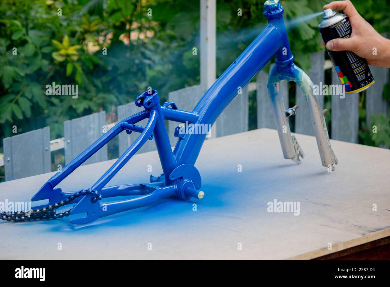 Spray Painting a Bicycle Frame Outdoors. Stock Photo