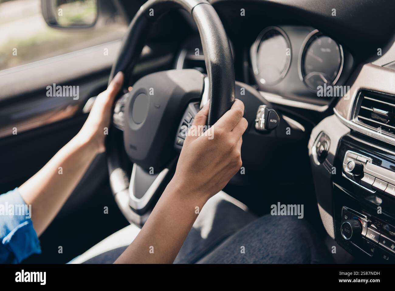 Young woman confidently driving a modern car during a sunny day ...