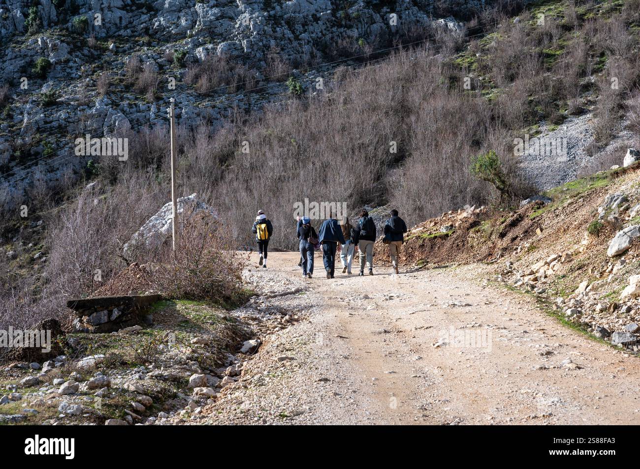 Mixed group of tourists walking a dirty gravel road on the Gamti Mountain in Albania, DEC 12, 2024 Stock Photo