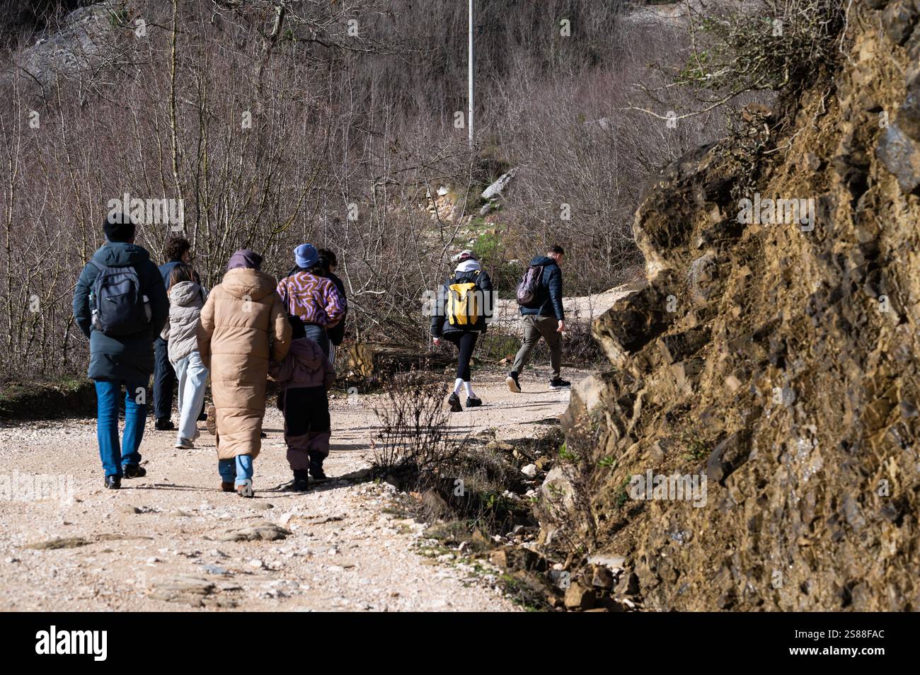 Mixed group of tourists walking a dirty gravel road on the Gamti Mountain in Albania, DEC 12, 2024 Stock Photo