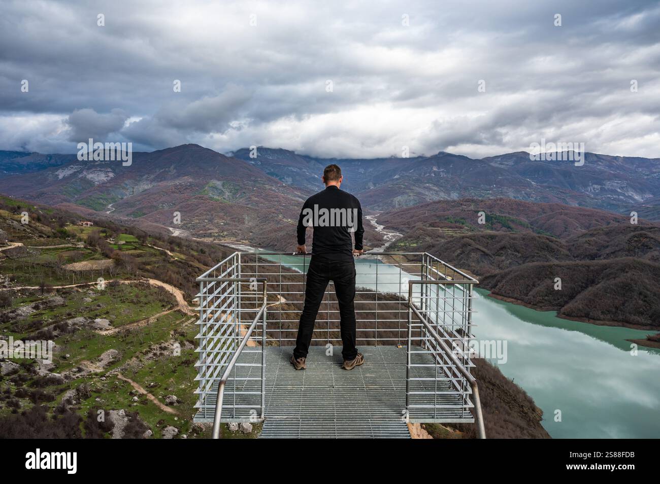 45 yo sporty tourist standing on a panoramic looking platform at the Gamti mountains and Bovilla lake, Albania. Model released Stock Photo