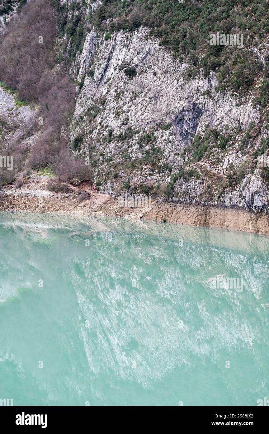 Granite texture of Gamti mountain flank reflecting in the blue water of the Bovilla lake, Albania Stock Photo