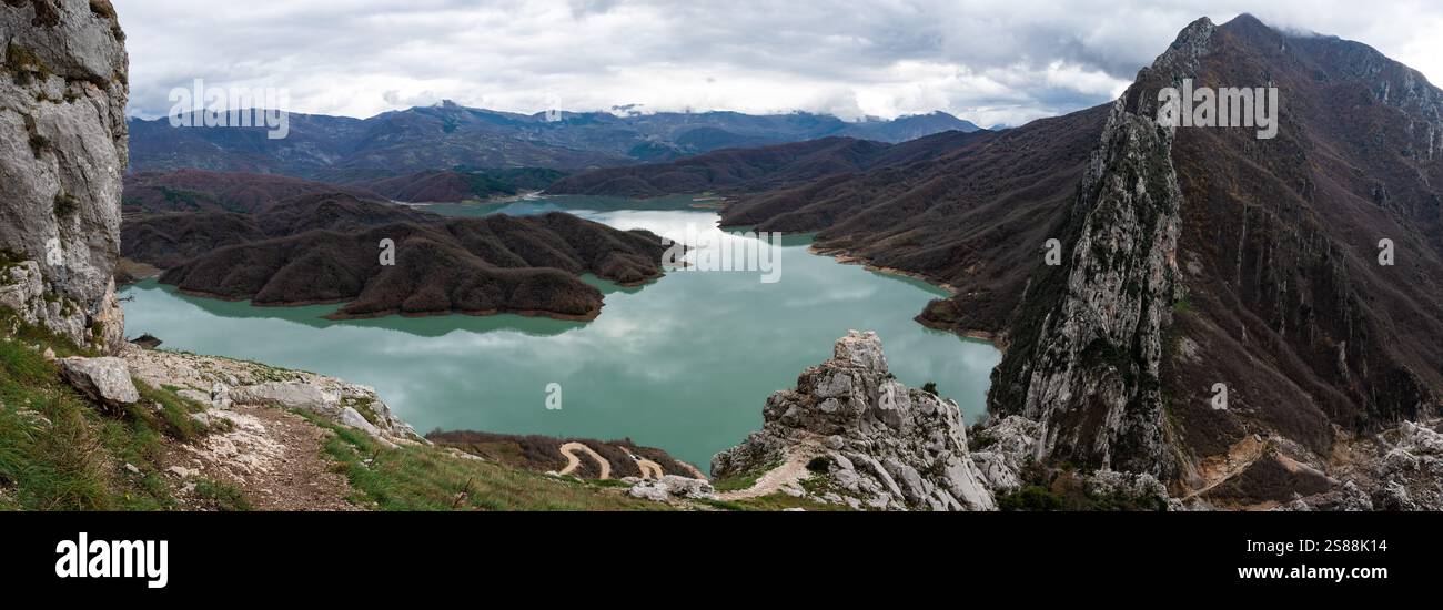 Scenic panoramic view over the Gamti mountains and Bovilla lake with colorful begetation, blue water and an overcast sky, Albania Stock Photo