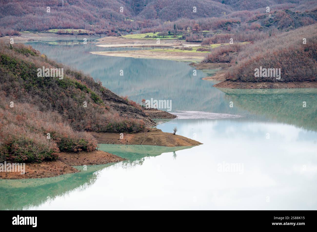 Scenic panoramic view over the Gamti mountains and Bovilla lake with colorful begetation, blue water and an overcast sky, Albania Stock Photo