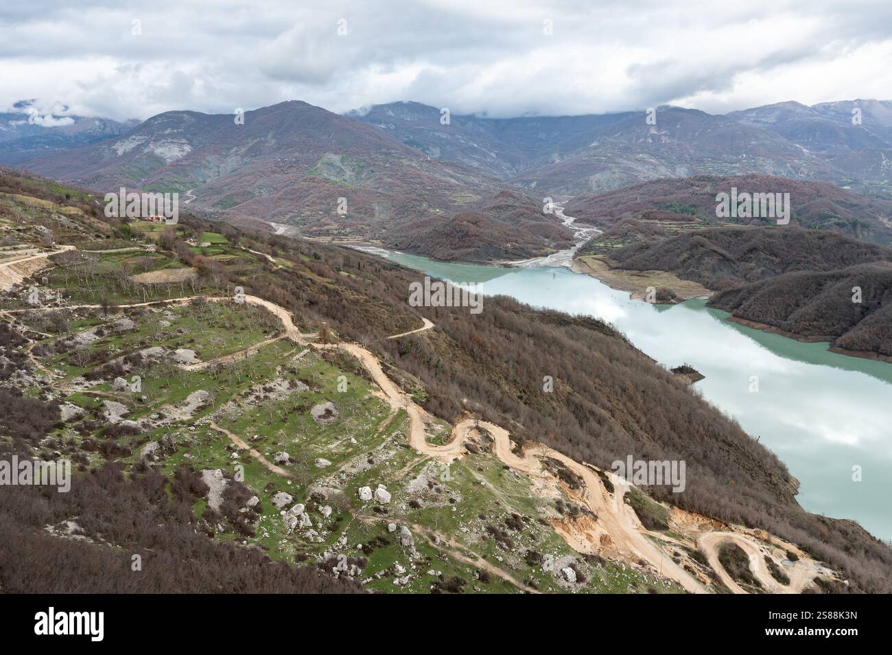 Scenic panoramic view over the Gamti mountains and Bovilla lake with colorful begetation, blue water and an overcast sky, Albania Stock Photo