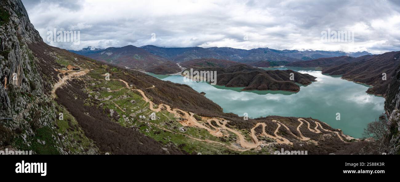 Scenic panoramic view over the Gamti mountains and Bovilla lake with colorful begetation, blue water and an overcast sky, Albania Stock Photo