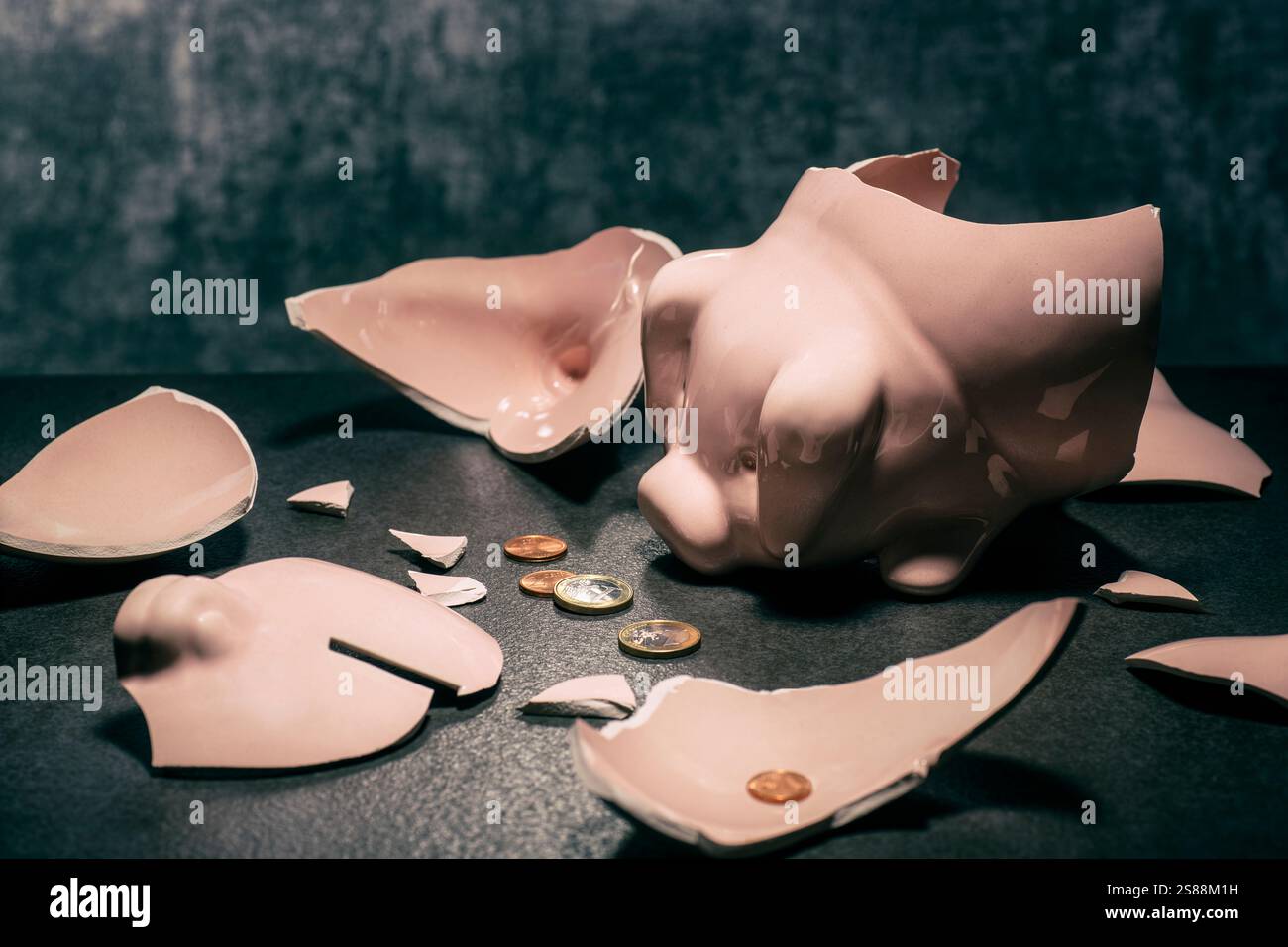 Broken piggy bank with a few coins on the floor Stock Photo