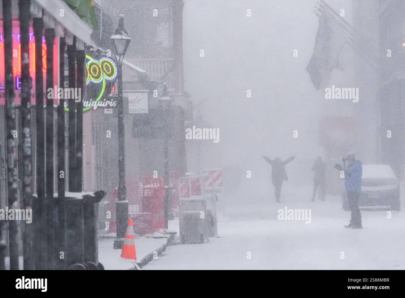 People walk around on Bourbon Street as snow falls in the French